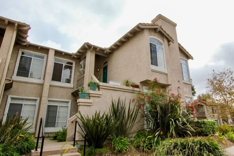 A large tan house with the numbers 428 is in a Lomas De Oro Community.