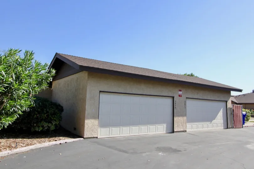 Two large garage doors with squares near a driveway at Los Arbolitos in Oceanside CA