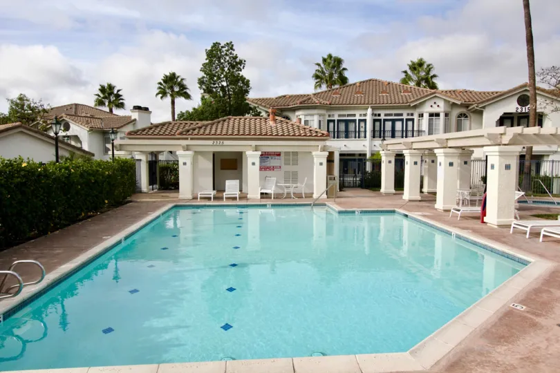 A giant mansion with a pool. It looks to be warm and sunny.