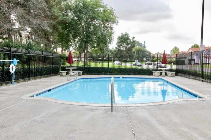 A pool with some tables by a tree at Mission Meadows in Oceanside, CA