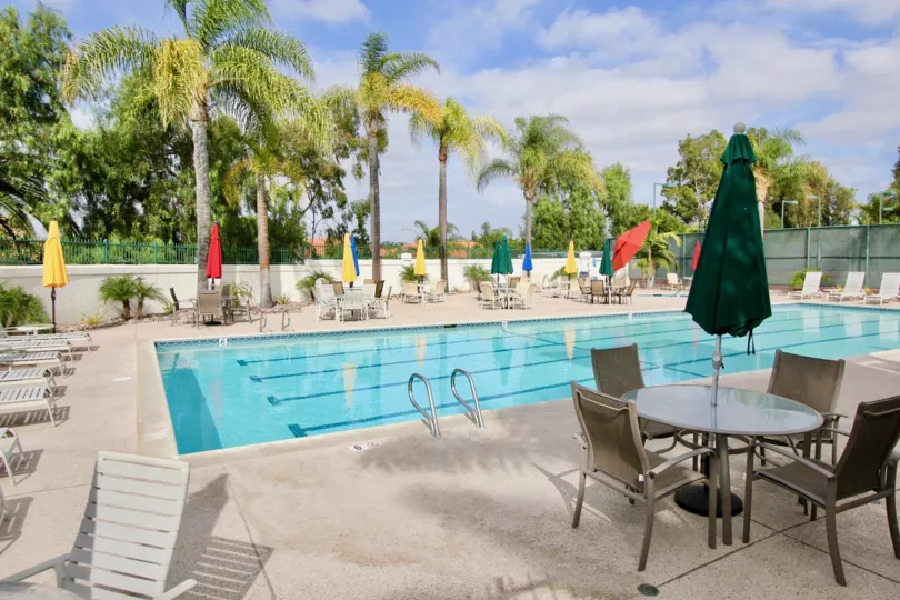 Pool view with colorful poolside umbrellas and loungers at Mission Point Townhomes in Oceanside, California