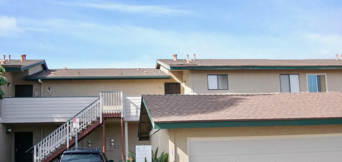 A house with red tiles with sunrays falling on the roof of the house with a black SUV parked infront at Mission vista