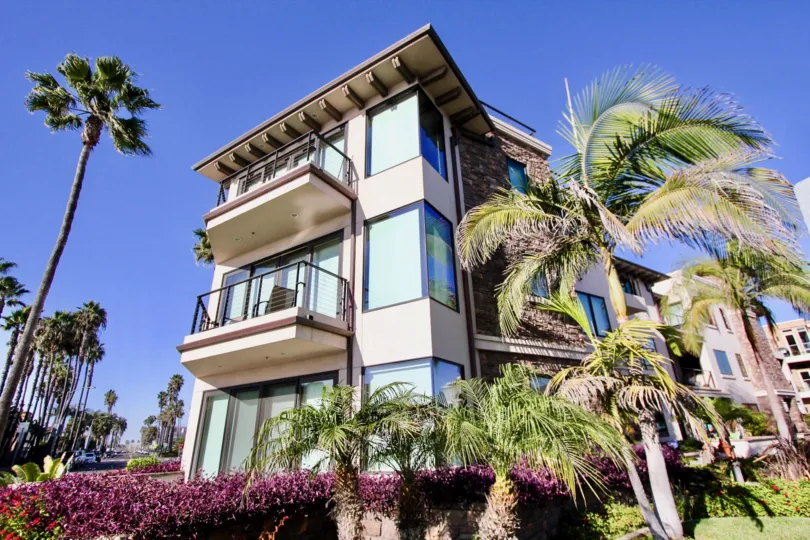 Three-story condos with large corner windows surrounded by palm trees at Montego Condominiums in Oceanside, CA