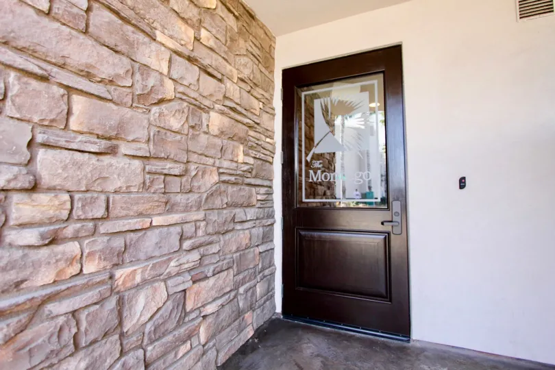 A stone wall by a door leading to the office of Montego Condominiums in Oceanside, CA