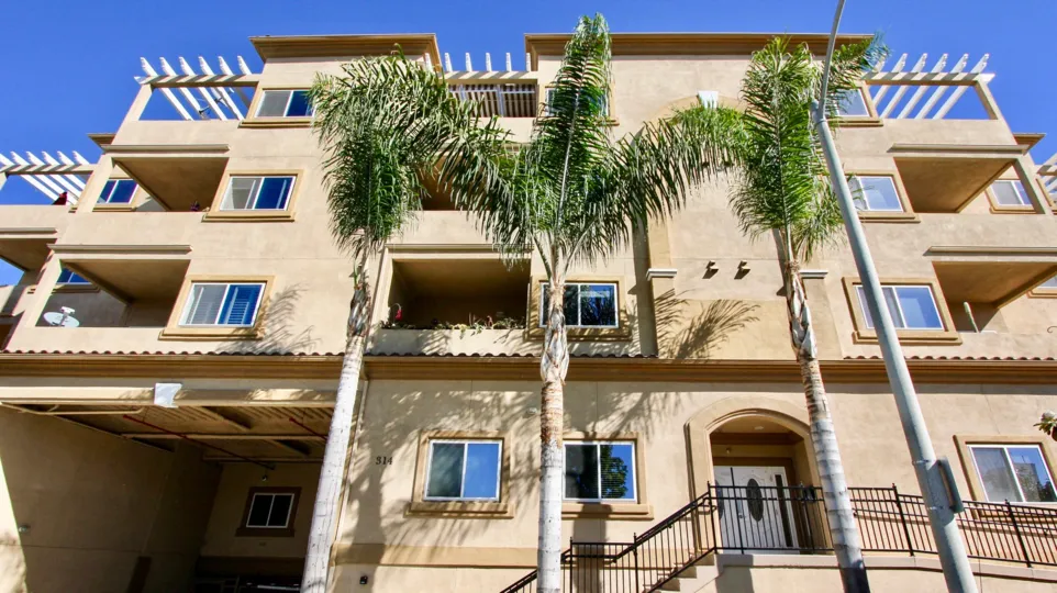 Three palm trees sit in front of the Nevada Manor condos