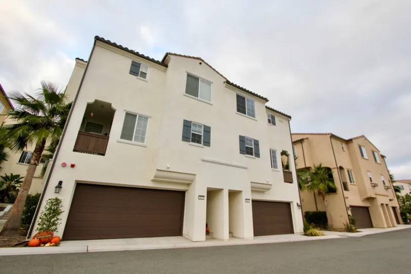 Beige house in North River Village community of Oceanside, California with two garages and palm tree landscape.
