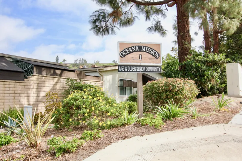 Plants around older senior community sign in Oceana Mission