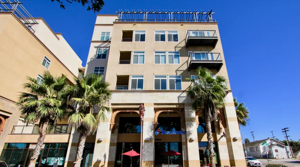 The exterior of the Oceanside Terrace building with a Domino's Pizza on the ground floor and palm trees in front.