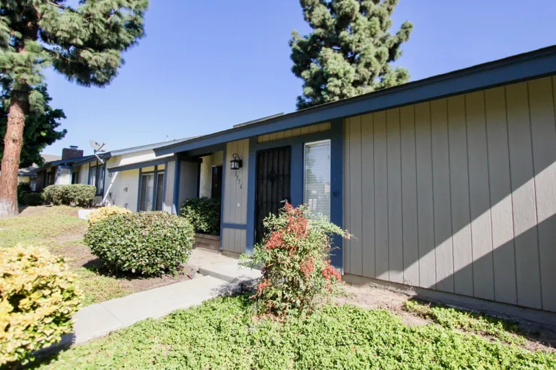 Single story blue home near a yard and plants in Oceanside Ca at Orchard lane