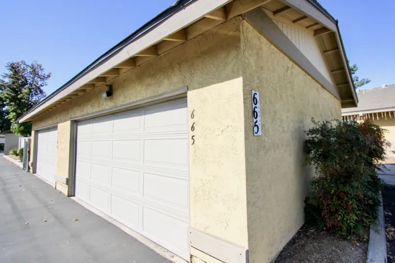 Single story brown garage with plants on the side in Oceanside CA at Orchard Lane