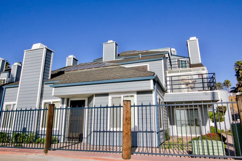 A sunny day in the area of Pacifica Strand, iron rod fence, sidewalk, balcony, table, chairs, door, chimney