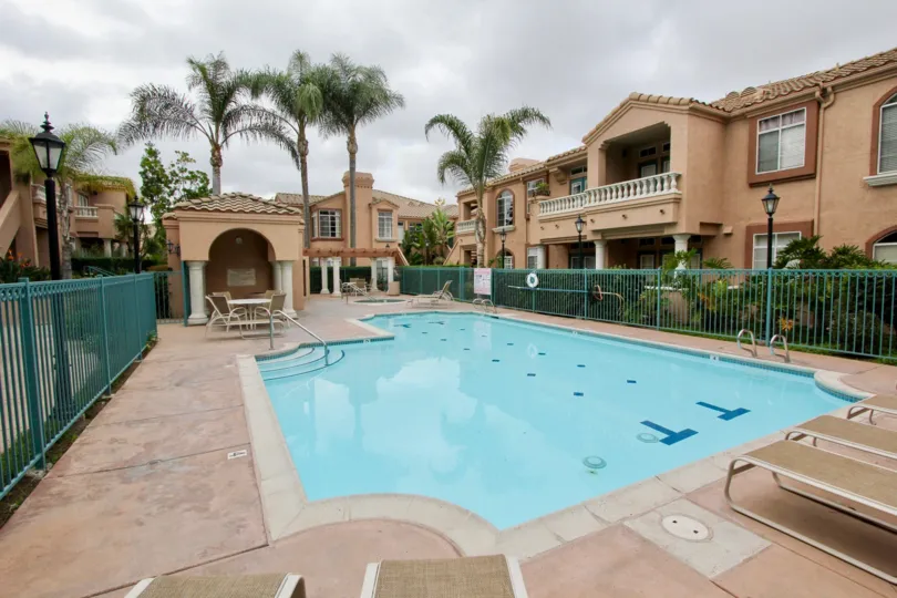 A sunny day poolside in the area of Palmilla Del Oro, table chairs, palm trees, stairs, fence