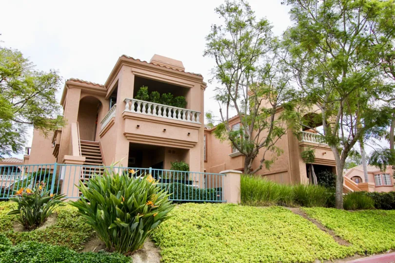 Two story pink units behind a blue fence on a hillside at Palmilla Del Oro in Oceanside CA