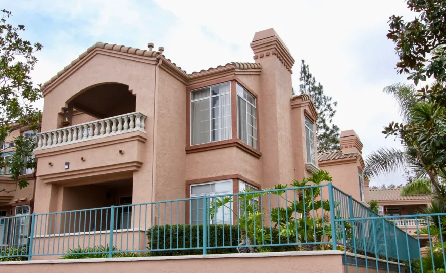 Large two story red stone apartments with large windows and fenced in lawns atPalmilla Del Oro