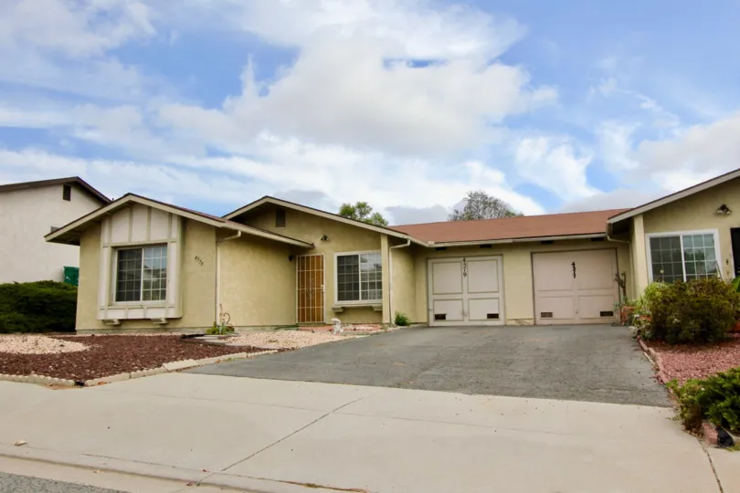 Blue skies and cloud cover over duplex with car garages in Peacock Hills.
