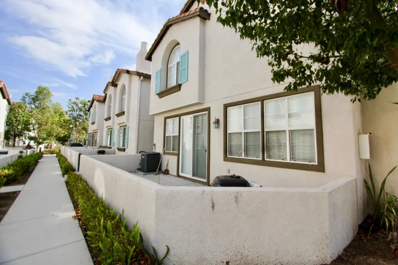 Two story housing behind a white wall & sidewalk in Pelican Cove in Oceanside CA