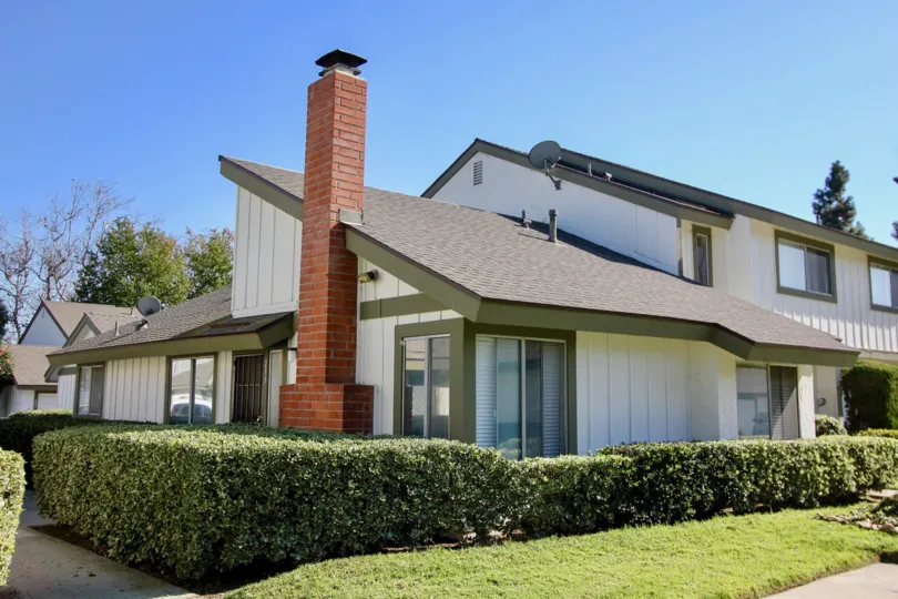 A large red brick chimney sits on the side of a building with vertical siding at Pepperwood Villas