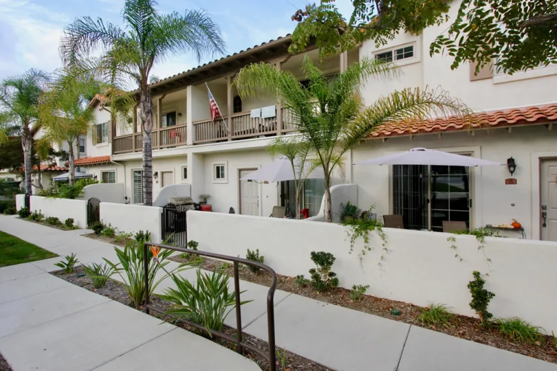 Large white two story homes with white and red trim and foliage at Rancho Rose.