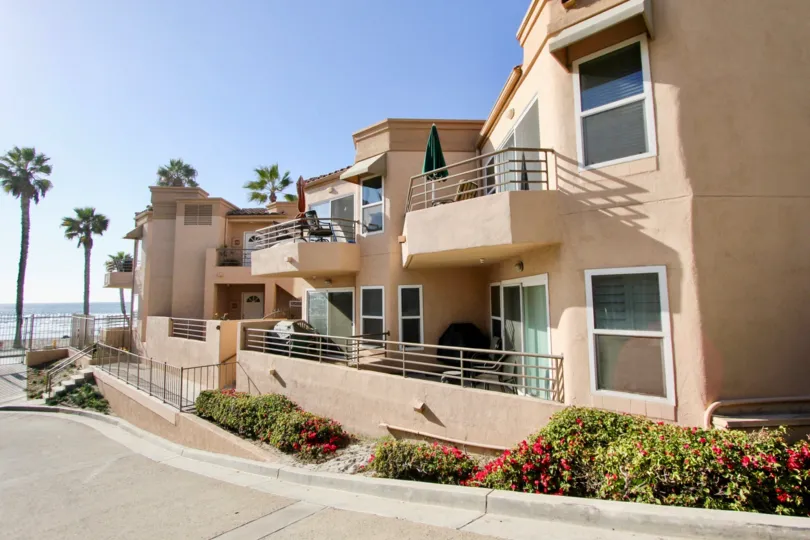 Two story pink homes lined with plants near the ocean at San Miguel III in Oceanside CA