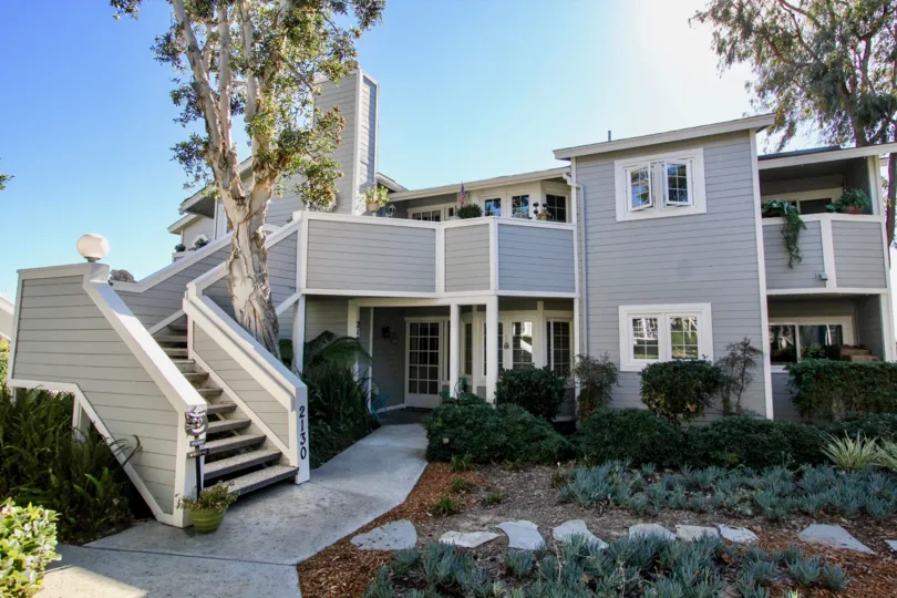 Gray two story building with a rock walkway garden inside Sandpiper Cove in Oceanside CA