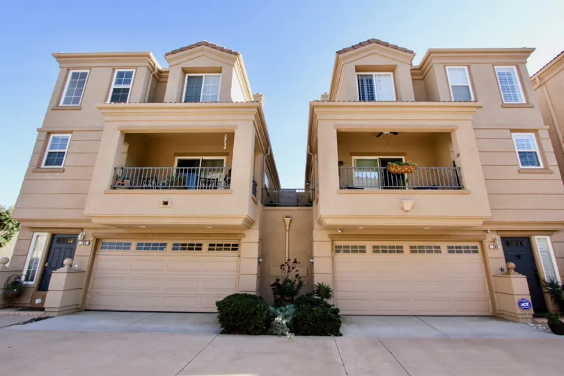 Three story brown homes with garages at their base inside Sea Breeze Beach Cottages in Oceanside Ca