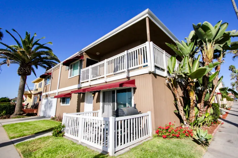 Two story wooden building with white rails in Oceanside CA at Sea Spray Villas II