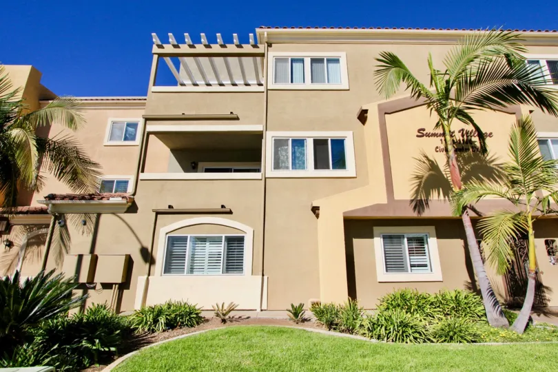 Cloudless blue skies overlooking Summit Village apartment homes with lush grass and palm trees.