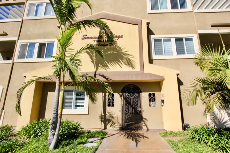 A sunny day in Summit Village with apartment building and palm trees.