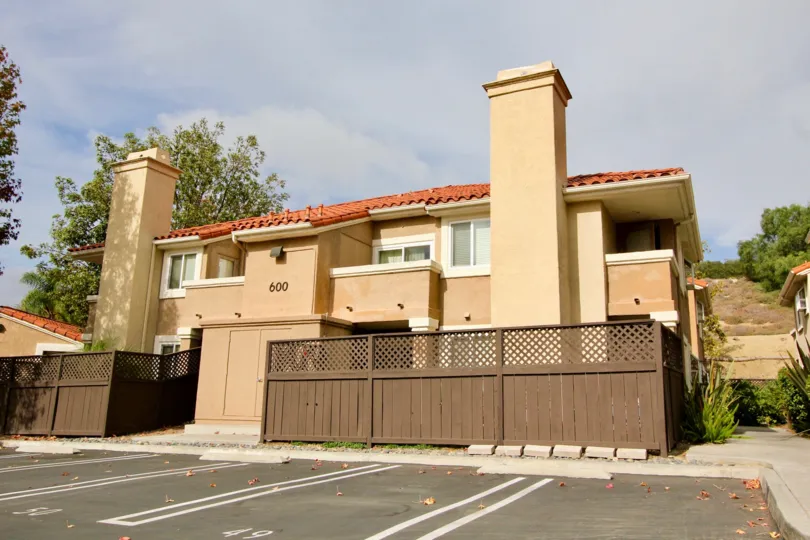 Brown wooden fence in front of a brown building with two chimneys in Oceanside CA at The Bluffs