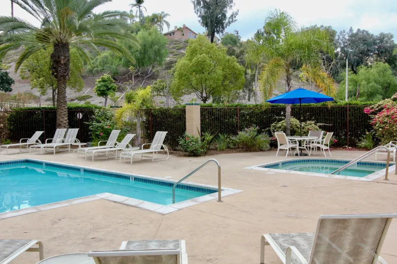 The private swimming pool and whirl pool with deck chairs and privacy fence at the Bluffs community.