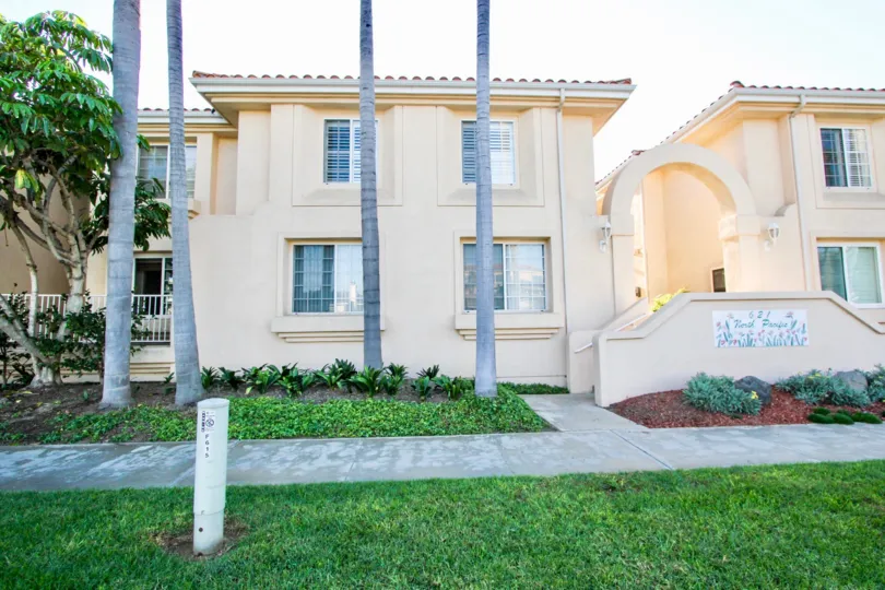 Well manicured lawns and tall palm trees and arched entryway at Villa Pacific