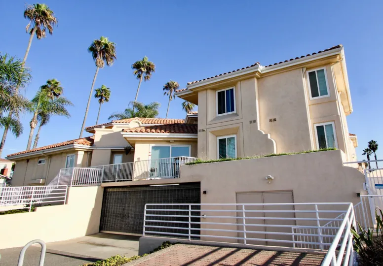 The Villa Pacific in Oceanside California is flanked by tall palm trees around its property.