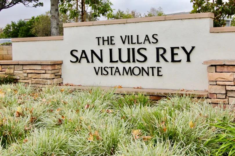 Tan sign behind grassy plants "the Villas San Luis Rey Vistamonte" Villa san luis rey oceanside California