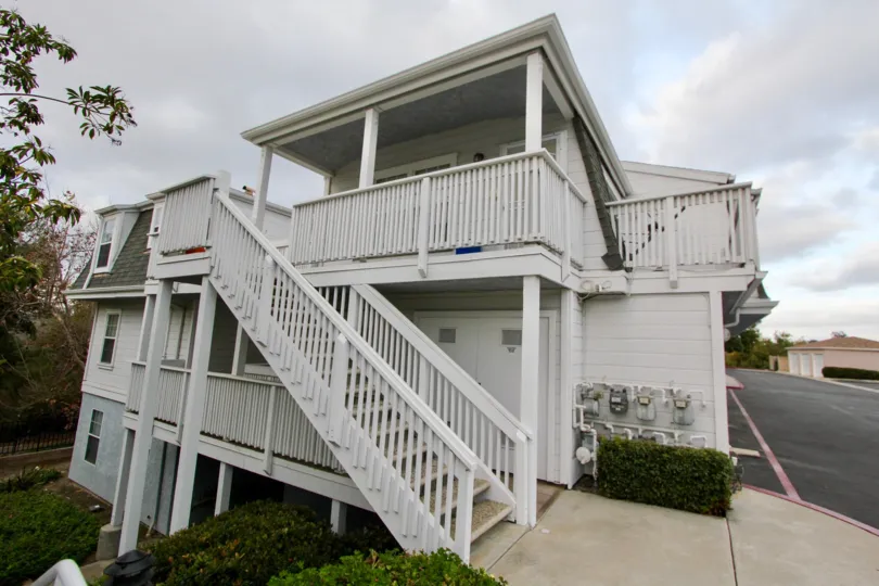 White three story home with multiple balconies and stairs, located in Villa San Luis Rey, Oceanside, California.
