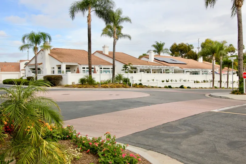 The view has many villas and trees with street and traffic signs board