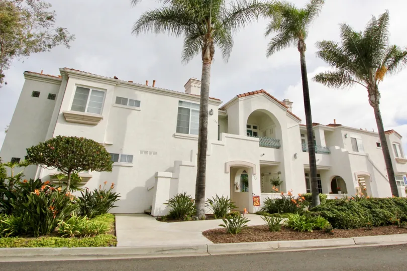 Two story white building behind Palms at Villa Trieste in Oceanside CA