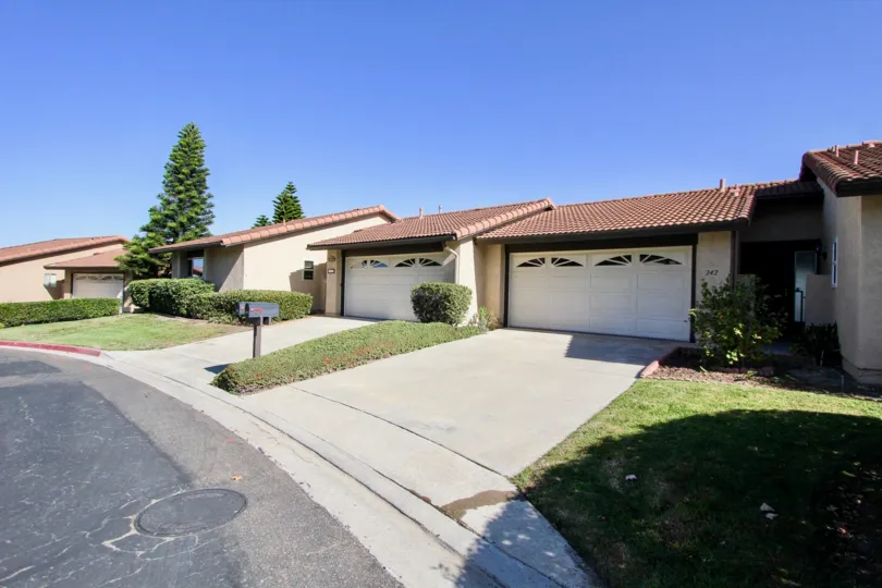 An exterior view of the Vista Montana condo homes with paved drive, two car garage, and recessed entrance.