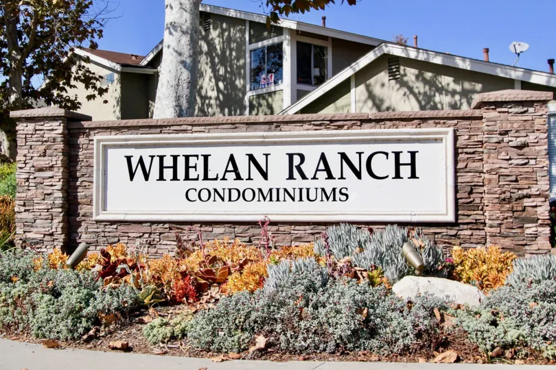 White and black sign on a stone wall in front of Whelan Ranch in Oceanside CA