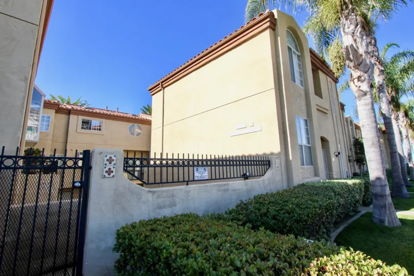 Short rectangle hedges sit in front of a gate at Wind & Sea Townhomes