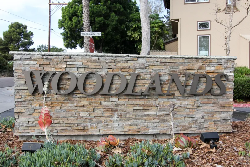 Stone wall design compound have word WOODLANDS in front of the buildings in Woodlands Ivy