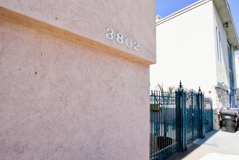 A pointy black gate between a pink building & a whie building at 3802 Riviera Condos in Pacific Beach CA