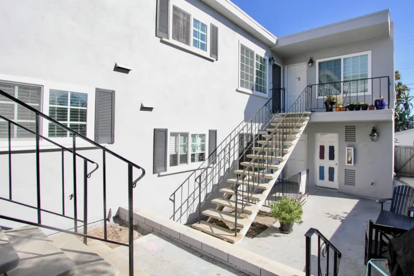 The sophisticated front side of a house with stairs and few windows in 839 Sapphire community is displayed.