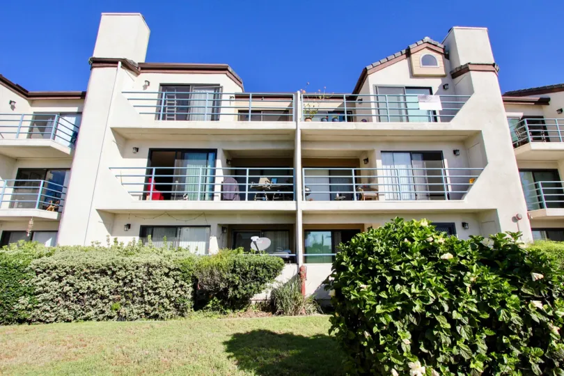 a housing with elegant and subtle look with a yard inn front with bushes, a clear day with a good view of the building
