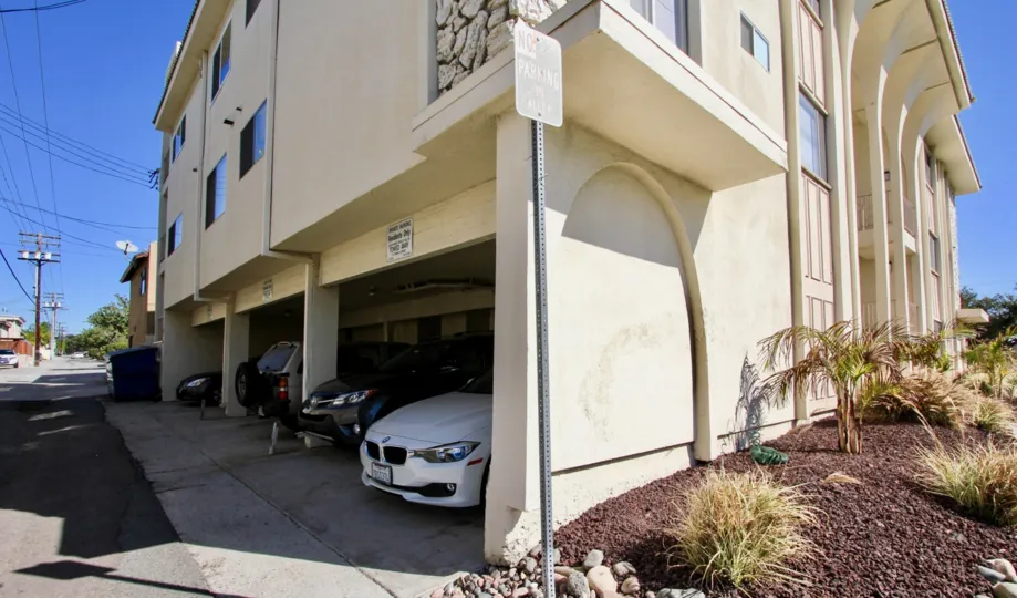 a big cream painted building with cars parked in the parking