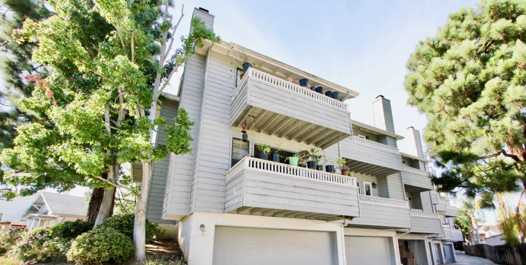 A contemporary housing in the Diamond by the Bay community with wooden cladding and chimneys.