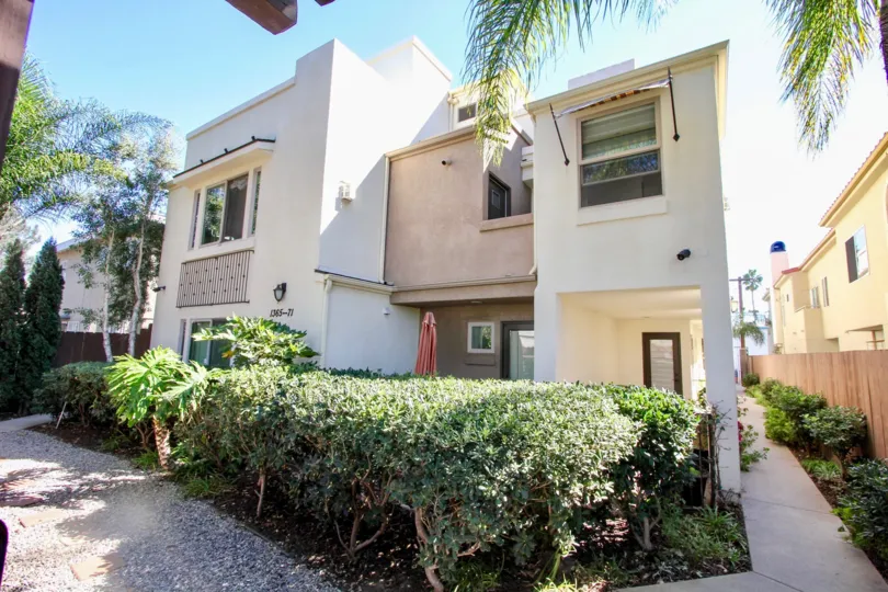 A beautiful back side of a building in the Hornblend Townhomes with some shrubs, plants and foot path.