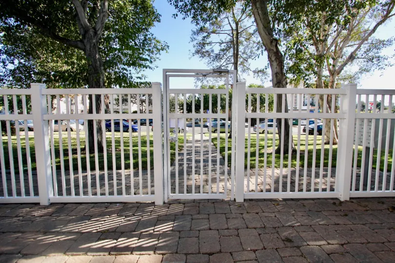 A sunny day in the area of Loring Manor, outside, brick walkway, fence, white, trees, cars