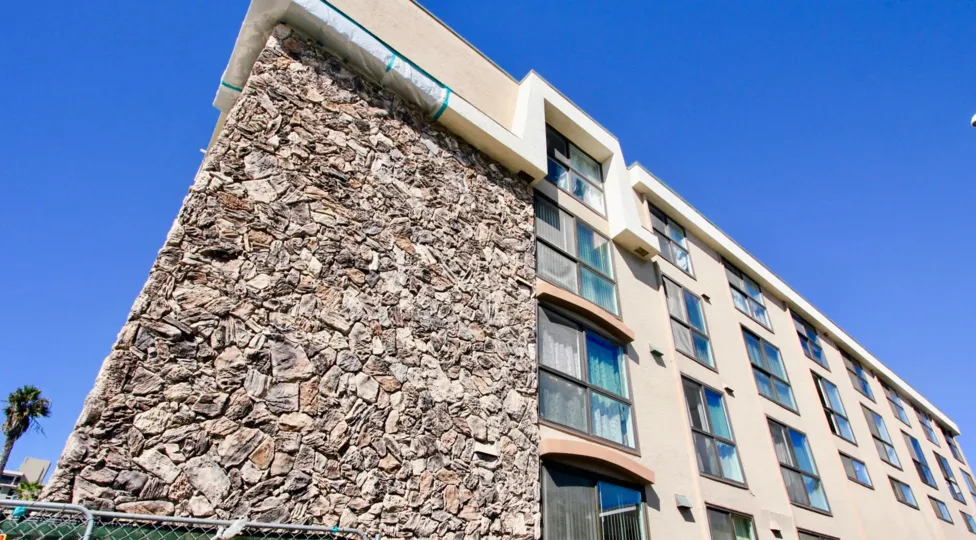 A mid-rise townhomes with stone cladding and sliding windows in the Ocean Point community.