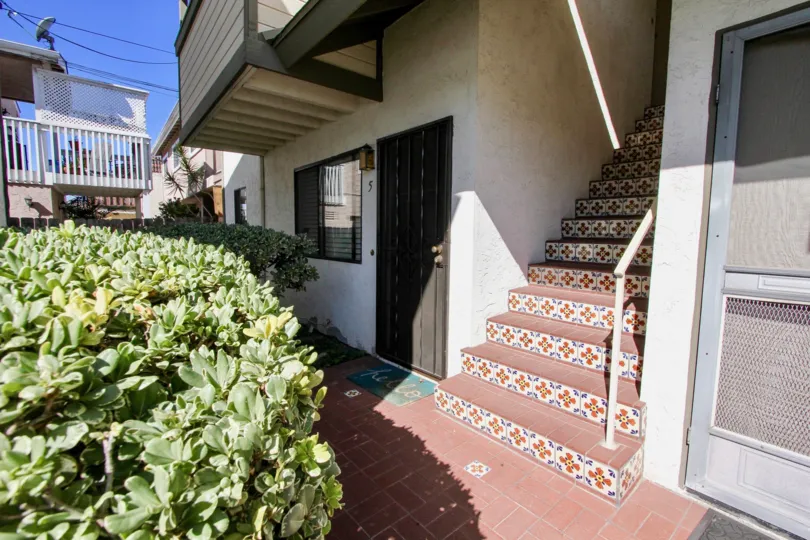 A low-rise residence in the Oliver Villas community with decorative staircase and wooden doors.