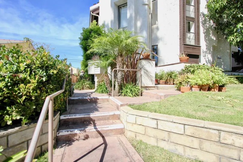 THE BUILDING IN THE OPAL TOWNHOMES WITH THE UPSTAIRS, LAWN, FLOWER POTS, TREES